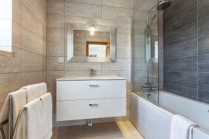 Modern bathroom with floating vanity, tile on floor and walls, and bathtub/shower combination