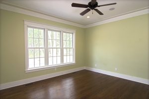 An empty bedroom with yellow walls and a set of double-hung windows on one wall.