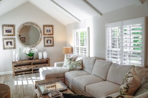 A living room with a beige sectional and vaulted ceilings