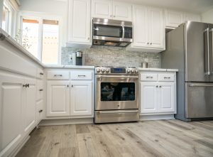 An updated kitchen with white cabinets and wood flooring