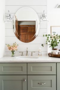 bathroom gray cabinets with wash basin and oval mirror shown in the picture